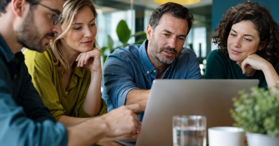 Team aus Mitarbeitenden bespricht Software-Optionen an einem modernen Konferenztisch im Büro