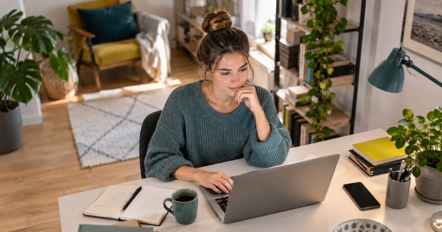 Person tippt konzentriert an Laptop, Chat-Fenster mit Textentwurf sichtbar im Hintergrund