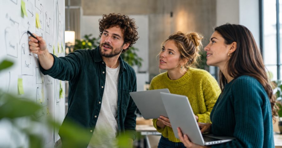Marketing-Team bespricht Aufgabenliste und Workflow an einem Whiteboard im Büro