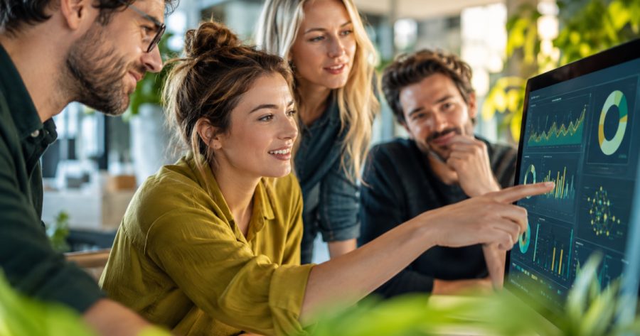 Marketing-Team schaut gemeinsam auf Bildschirm mit KI-Dashboard im Büro