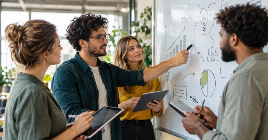 Marketing-Team bespricht Strategie-Anpassungen vor Whiteboard mit Diagrammen