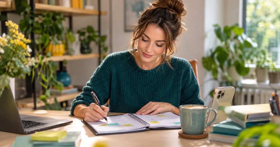 Person plant Instagram Postingplan im Kalender am Schreibtisch mit Smartphone