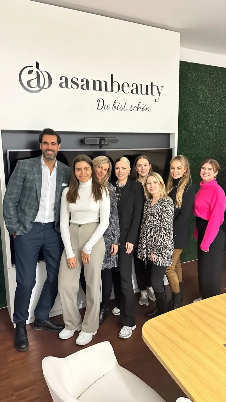 Alex Khan mit dem Marketing-Team von asambeauty vor der Markenwand nach dem Workshop