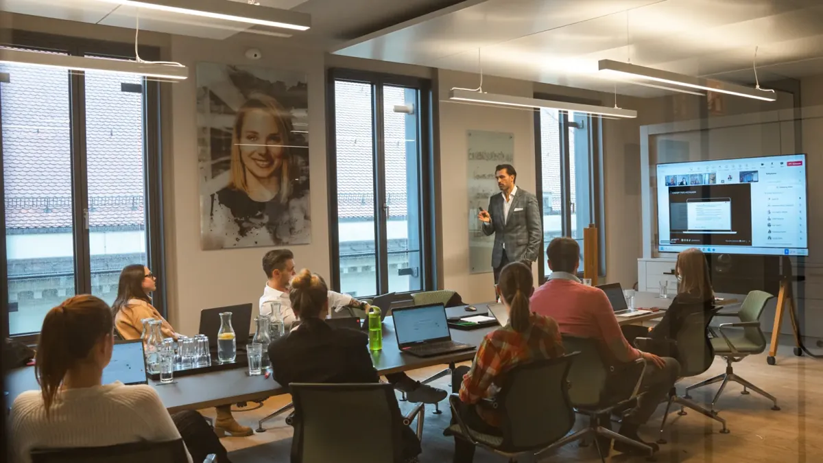 Alex Khan leitet einen KI-Workshop bei der Lenyx Group, die Teilnehmenden arbeiten an Laptops
